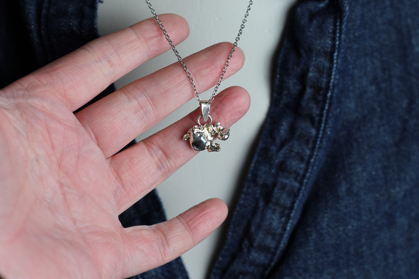 Dainty artisan silver necklace featuring a unique melted texture and a brilliant royal blue sapphire accent, showcasing slow jewelry craftsmanship.