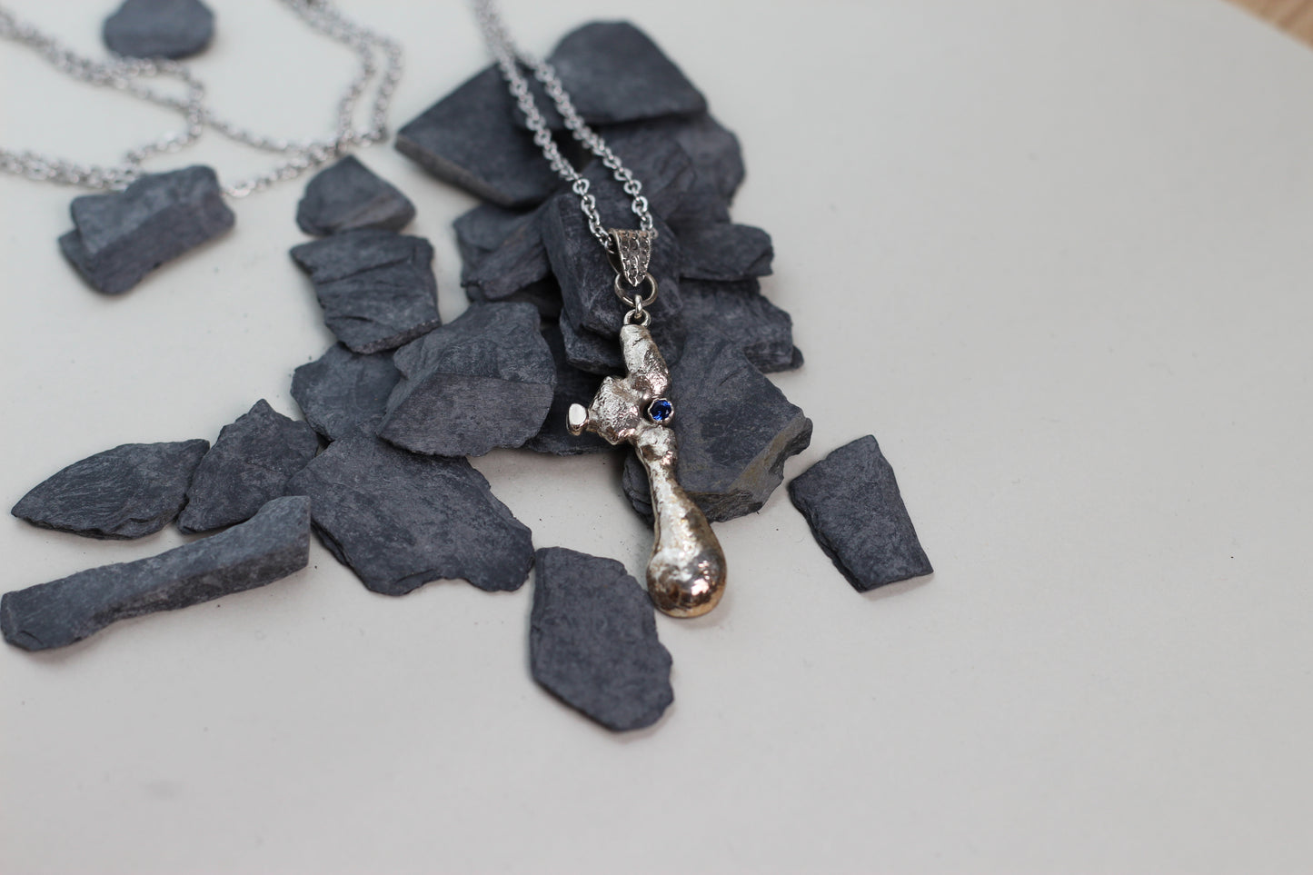 Massive textured 925 silver statement pendant with a blue sapphire stone worn on a classic silver chain against a simple white t-shirt.
