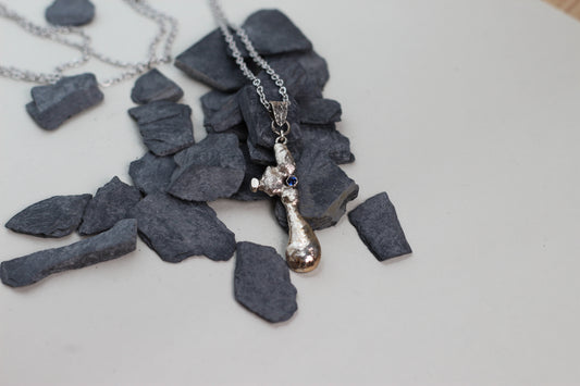Massive textured 925 silver statement pendant with a blue sapphire stone worn on a classic silver chain against a simple white t-shirt.
